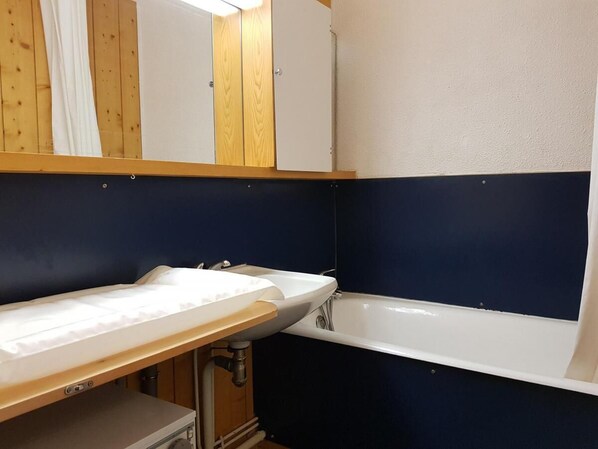 Een badkamer met een wit wastafel, een badkuip en houten kastjes.