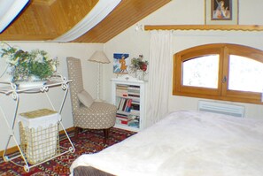 Relax in a peaceful retreat with a comfortable chair, bookshelf, and plush bed.