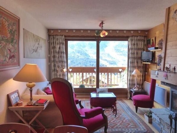 Relax in a cozy room with a scenic mountain view, featuring a comfortable reading area, TV, and fireplace.