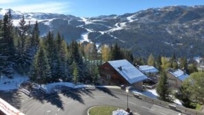 A mountain lodge with a snow-covered roof, surrounded by evergreen trees and a view of snow-capped mountains. - 200m from ski slopes, 4th floor, view mountain, balcony, fireplace or stove, tv, ski locker, 56m² (Méribel - Les Allues)