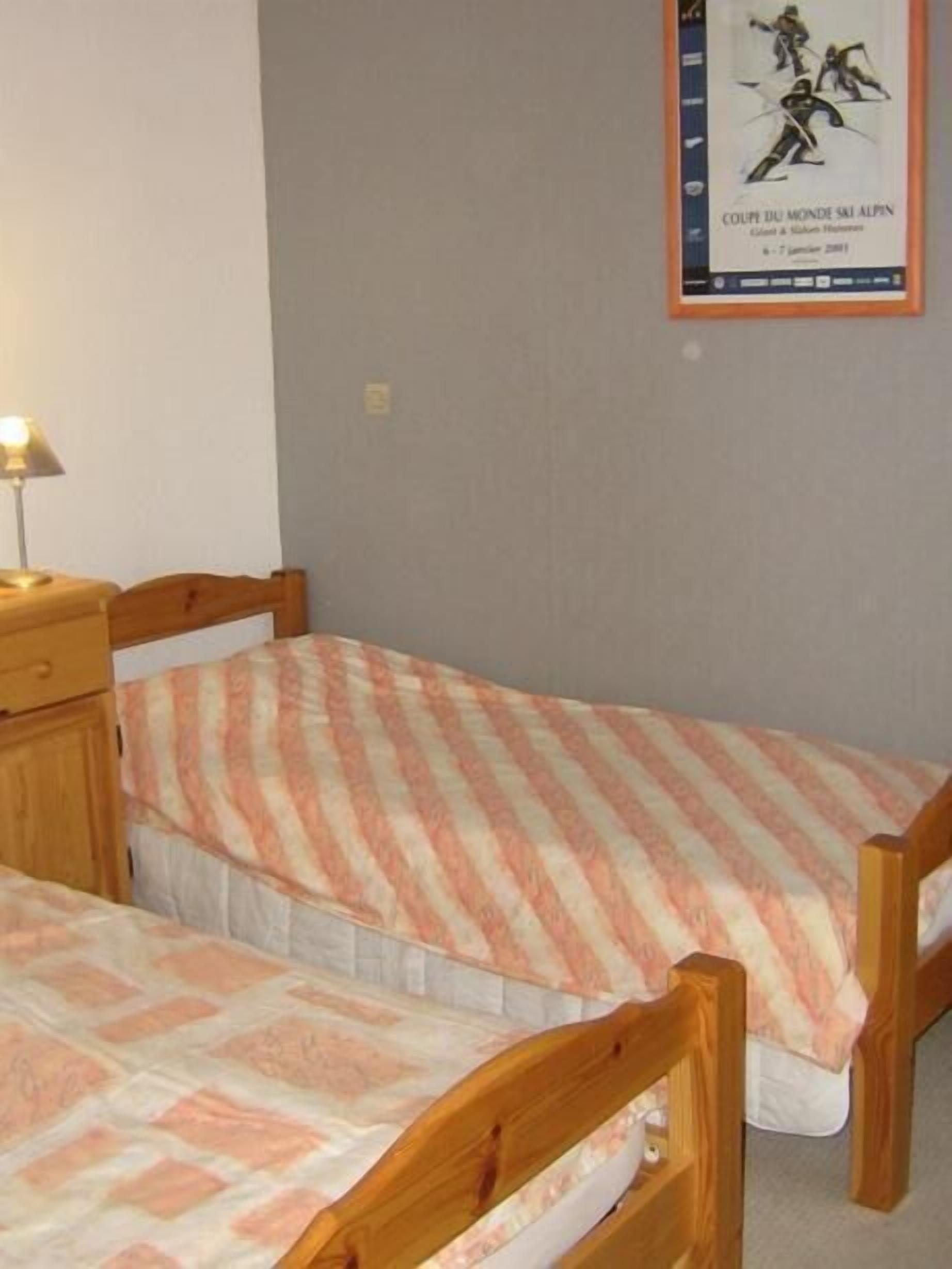 Ein Schlafzimmer mit zwei Einzelbetten, einem Nachttisch und einem Poster an der Wand.