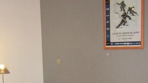 Een slaapkamer met twee eenpersoonsbedden, een nachtkastje en een poster aan de muur.