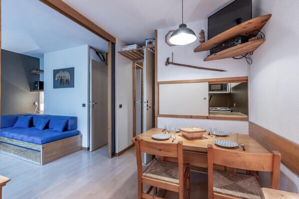 A compact living space with a dining area, a blue sofa, and a wooden dining table with chairs. - 50m from ski slopes, 1st floor, terrace, tv, ski locker, 27m², Montchavin La Plagne (Bellentre)