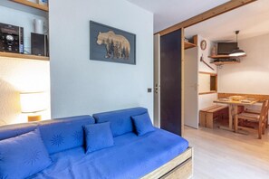 Una habitación con un sofá azul, una mesa de comedor de madera y una decoración de pared con temática de osos.
