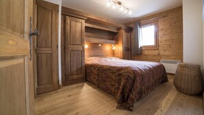 A bedroom with a bed, wooden walls, a window, and a radiator. - 2nd floor, view mountain, swimming pool, balcony, tv, ski locker, 55m², Les Arcs (Bourg-Saint-Maurice)