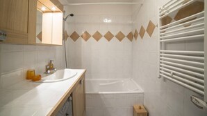A modern bathroom with a white sink, mirror, and shower. - 2nd floor, view mountain, swimming pool, balcony, tv, ski locker, 55m², Les Arcs (Bourg-Saint-Maurice)
