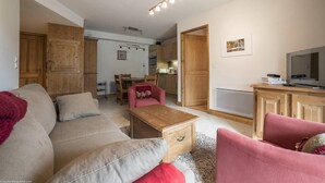 A living room with a sofa, a coffee table, a TV, and wooden cabinets. - 2nd floor, view mountain, swimming pool, balcony, tv, ski locker, 55m², Les Arcs (Bourg-Saint-Maurice)
