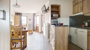 A compact kitchen with wooden cabinets, a microwave, and a refrigerator. - 6th floor, view mountain/mountain/ski slopes, balcony, tv, ski locker, 27-26m², Les Menuires (Les Menuires)