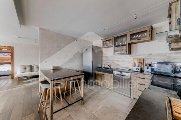 A modern kitchen with a central island, wooden cabinets, and a built-in oven. - Resort center, floor -1, view mountain, balcony, tv, 140m², Méribel (Méribel - Les Allues)