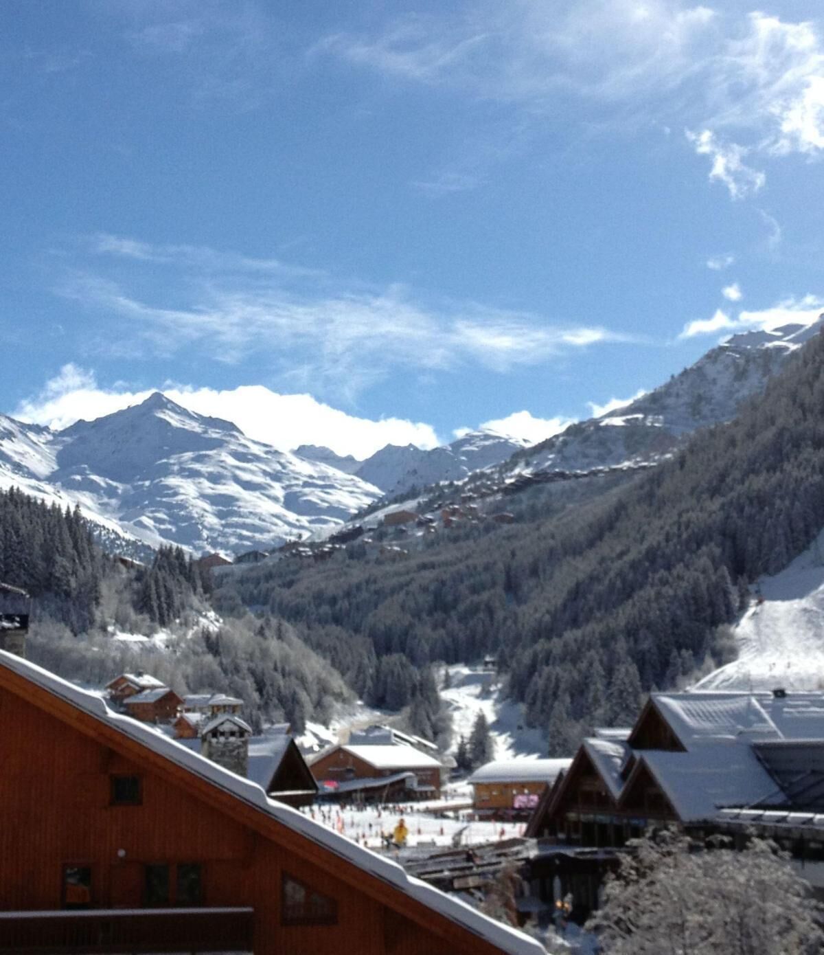 A mountain lodge with a view of snow-covered peaks and a forested valley.