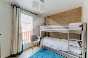 Een slaapkamer met stapelbedden en uitzicht op gebouwen.