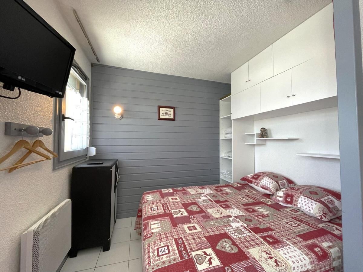 A bedroom with a bed, a dresser, a TV, and a radiator.