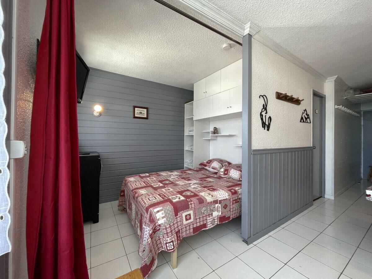 Une chambre à coucher avec un lit, une armoire et un rideau rouge.