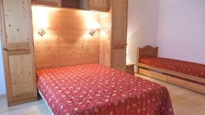 A bedroom with a bed, a bench, and wooden cabinets.