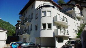 A multi-story building with balconies, a garage, and a mountain backdrop.