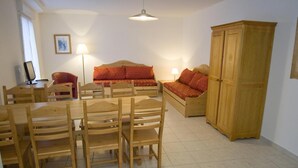 A dining area with a wooden table and chairs, a sofa, and a cabinet.