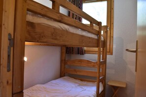 A bunk bed with a shelf above and a small wooden table beside it. - 150m from resort center, 2nd floor, view mountain, balcony, ski locker, 40m², Méribel (Méribel - Les Allues)