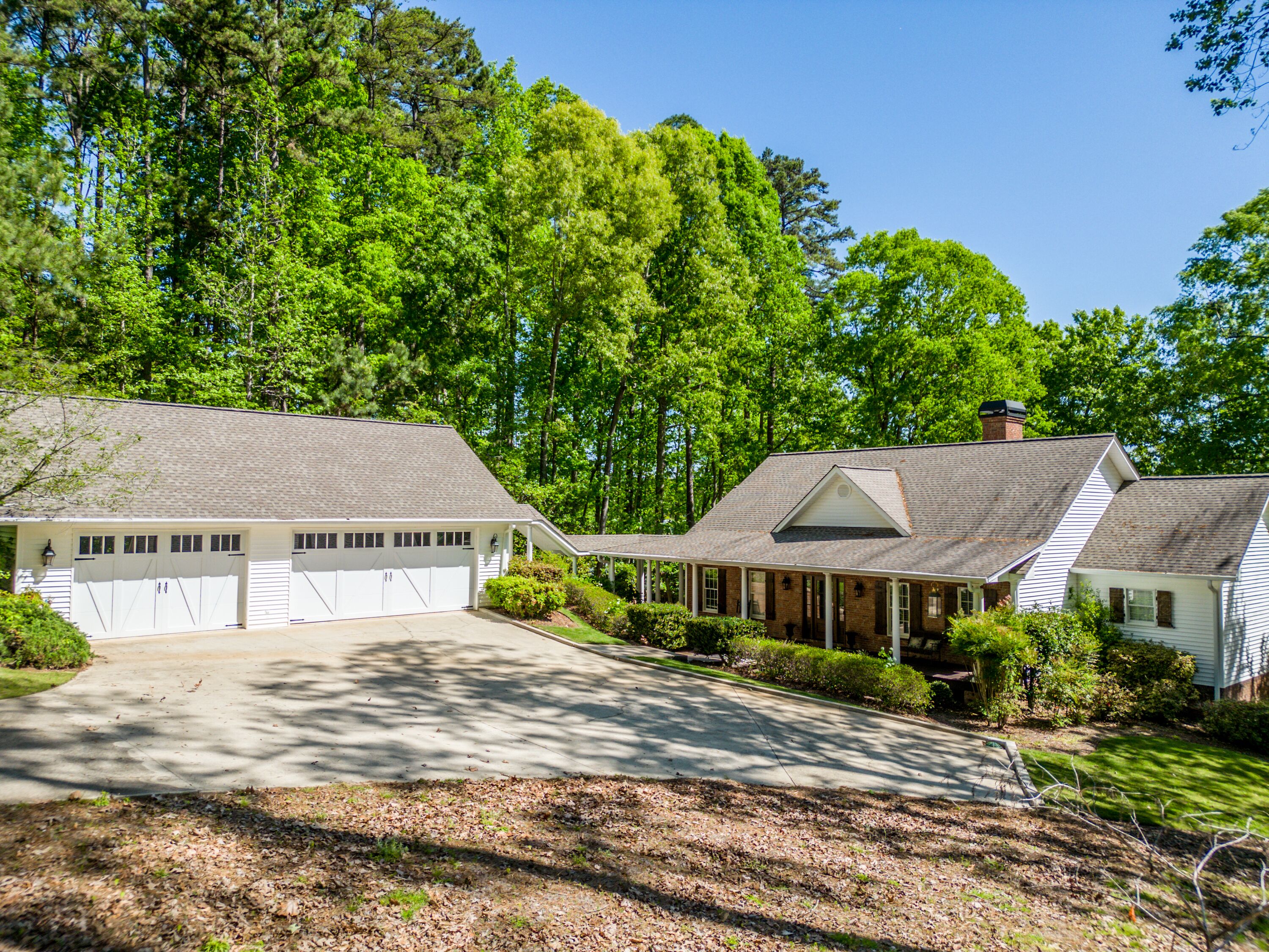 A two-story house with a garage, surrounded by a well-maintained lawn and dense trees.