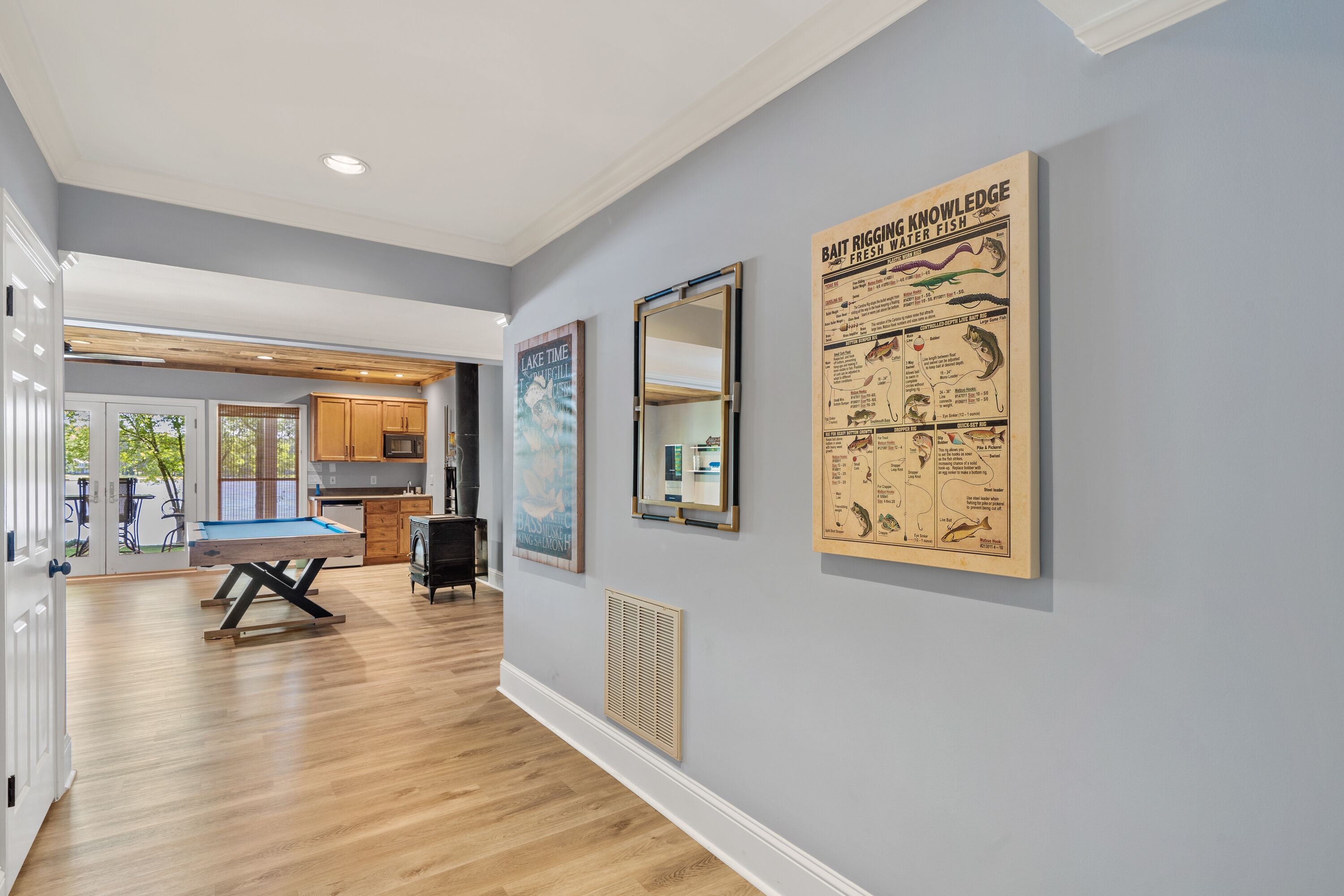 A modern kitchen with wooden cabinets, a dining table, and a pool table.