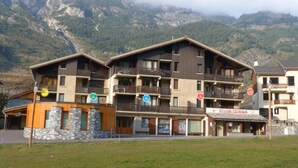 A multi-story hotel with balconies, a restaurant, and a view of mountains.