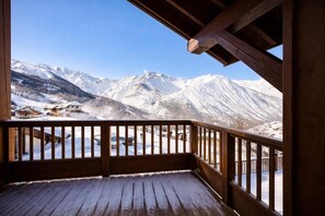 A wooden balcony with a view of snow-covered mountains and a small village below. - 100m from ski slopes, 3rd floor, balcony, parking, tv, 68m², Saint Martin de Belleville (Saint-Martin-de-Belleville)