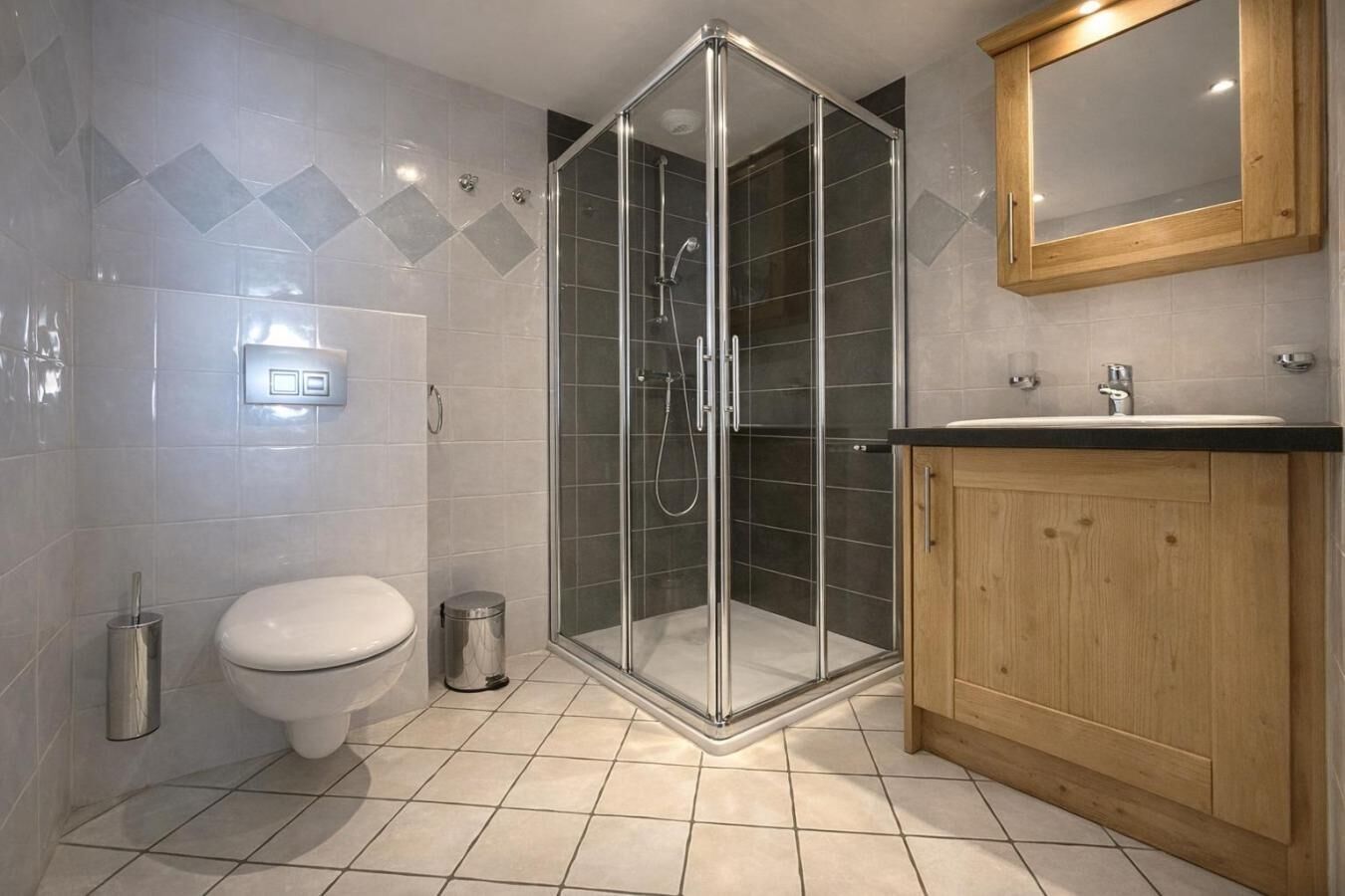 Une salle de bain moderne avec une douche à parois de verre, des toilettes, un lavabo avec un meuble en bois et un miroir au-dessus du lavabo.