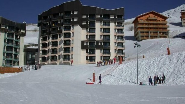 Un hôtel à plusieurs étages, doté d’une architecture moderne, situé dans une région montagneuse enneigée.