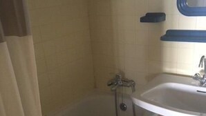 A bathroom with a bathtub, a sink, and a mirror.