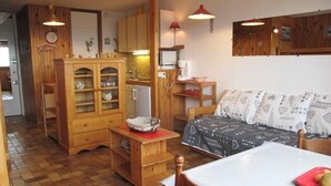 A cozy kitchen with wooden cabinets, a dining table, and a sofa.