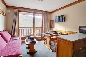 Una habitación acogedora con sofá, mesa de comedor y televisor montado en la pared.