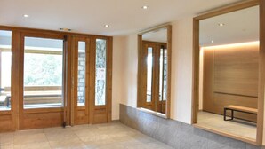 A spacious lobby with wooden doors, a bench, and a large mirror. - 20m from ski slopes, 1st floor, swimming pool, balcony, tv, ski locker, 24m², Méribel (Méribel - Les Allues)