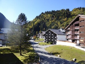A resort with multiple chalet-style buildings, a central road, and a mountainous backdrop.