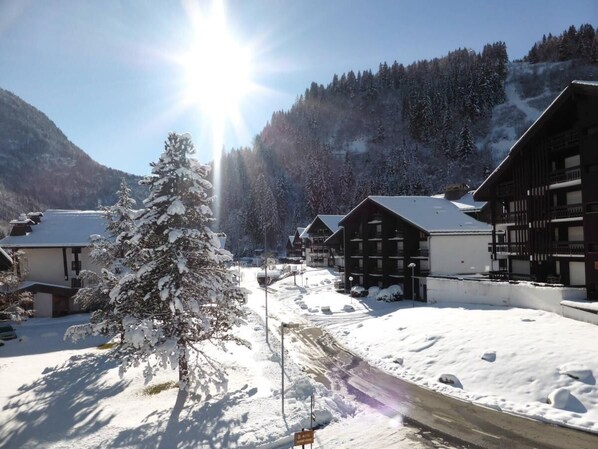 A snow-covered village with wooden buildings, a clear sky, and a sun shining.