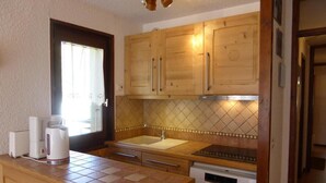 A compact kitchen with wooden cabinets, a sink, a stove, and a dishwasher.