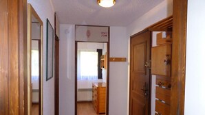 A narrow hallway with wooden doors and a mirror on the left.
