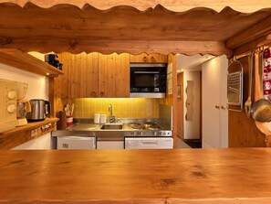 A kitchen with wooden cabinets, a microwave, a stove, and a sink. - 8th floor, view mountain, tv, 40m², Les Arcs (Les Arcs)