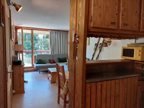 A wooden interior with a dining area, a sofa, and a view through large windows. - 8th floor, view mountain, tv, 40m², Les Arcs (Les Arcs)