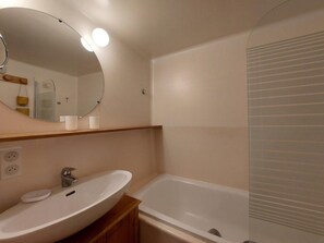 A bathroom with a white sink, mirror, and bathtub. - 8th floor, view mountain, tv, 40m², Les Arcs (Les Arcs)