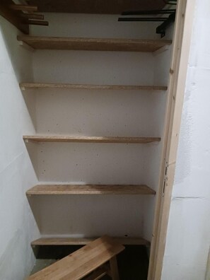 A narrow, white-walled room with a wooden staircase leading to a lower level.