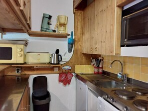 Une cuisine compacte équipée d’un four à micro-ondes, d’un grille-pain, d’une machine à café et d’un évier.