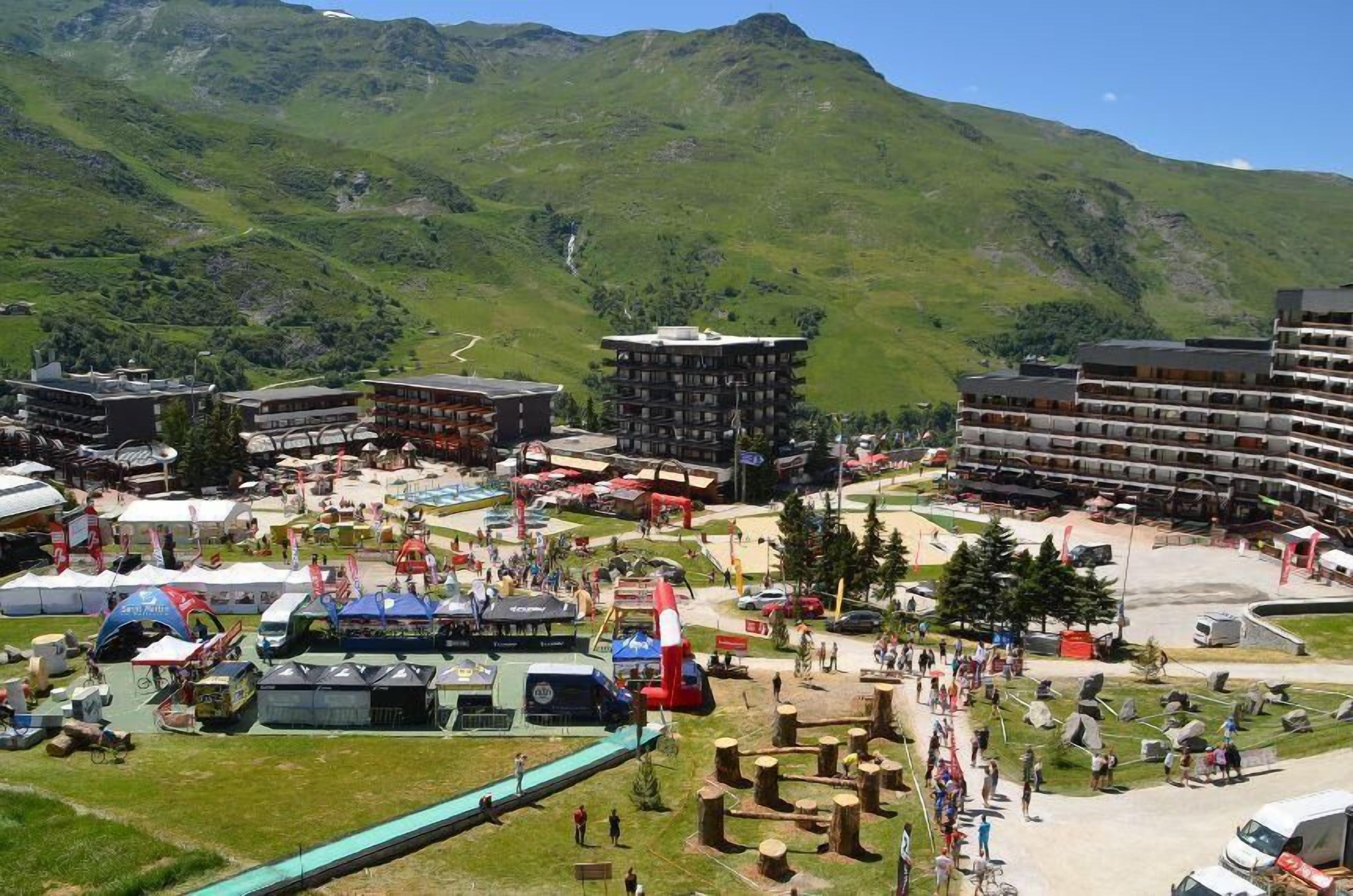 A mountainous area with a hotel complex, outdoor seating, and a ski lift.
