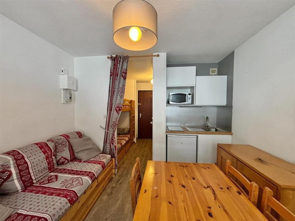 Un espace de vie compact comprenant un canapé, une table à manger en bois et un coin cuisine.