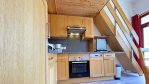 A compact kitchen with wooden cabinets, a built-in oven, and a small window. - 150m from ski slopes, view mountain, balcony, tv, 35m², Les Menuires (Les Menuires)