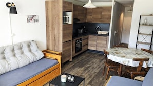 A compact living space with a sofa, a dining table, and a kitchenette.