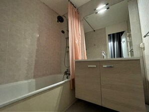 A bathroom with a bathtub, a shower, and a vanity with a mirror.