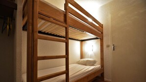 A bunk bed with a wooden frame, a single mattress, and a pillow.