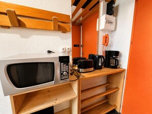 A kitchenette with a microwave, toaster, coffee maker, and a telephone. - 10m from ski slopes, 3rd floor, view ski slopes, balcony, tv, 24m², Les Menuires (Les Menuires)