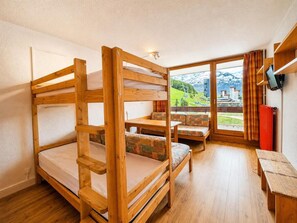 Ein Zimmer mit Etagenbetten, einer Couch, einem Tisch und Bergblick.
