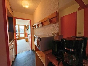 A narrow kitchen with a microwave, coffee maker, and wooden shelves. - 10m from ski slopes, 3rd floor, view ski slopes, balcony, tv, 24m², Les Menuires (Les Menuires)