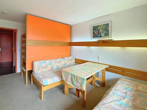 A room with a wooden bench, a small table, and a colorful quilted bench.